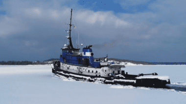 A boat navigating a lake coverd in snow and ice