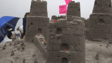 A sandcastle with three small towers and one large base.