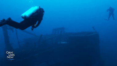 Two SCUBA divers investigate a sunken ship.