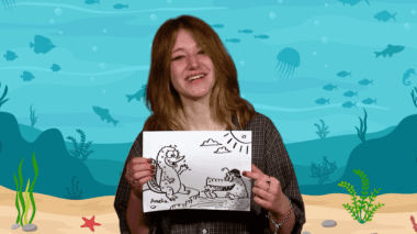 Amelia from Extra Credit holding a drawing of a platypus and crocodile.