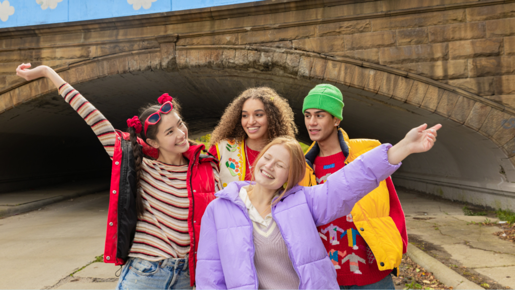 Four teens smiling under a bridge
