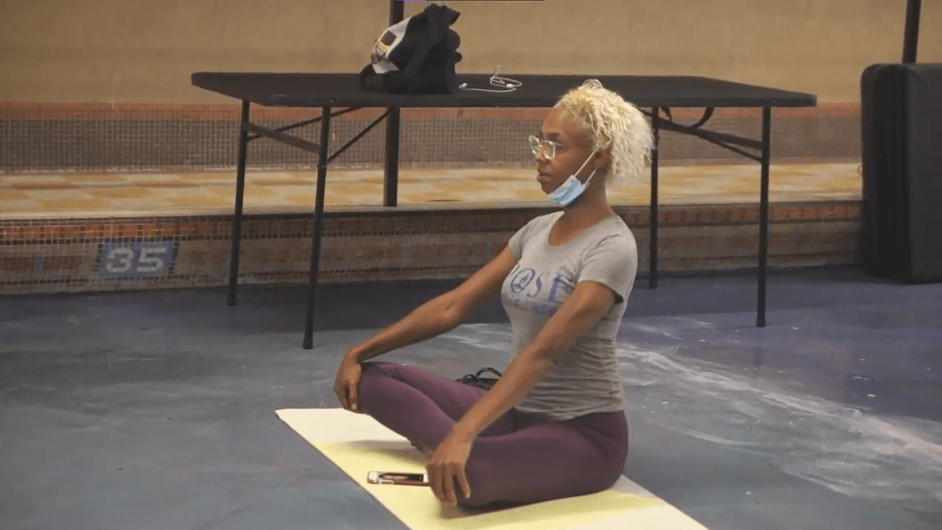 A woman sitting cross-legged on a yellow yoga mat