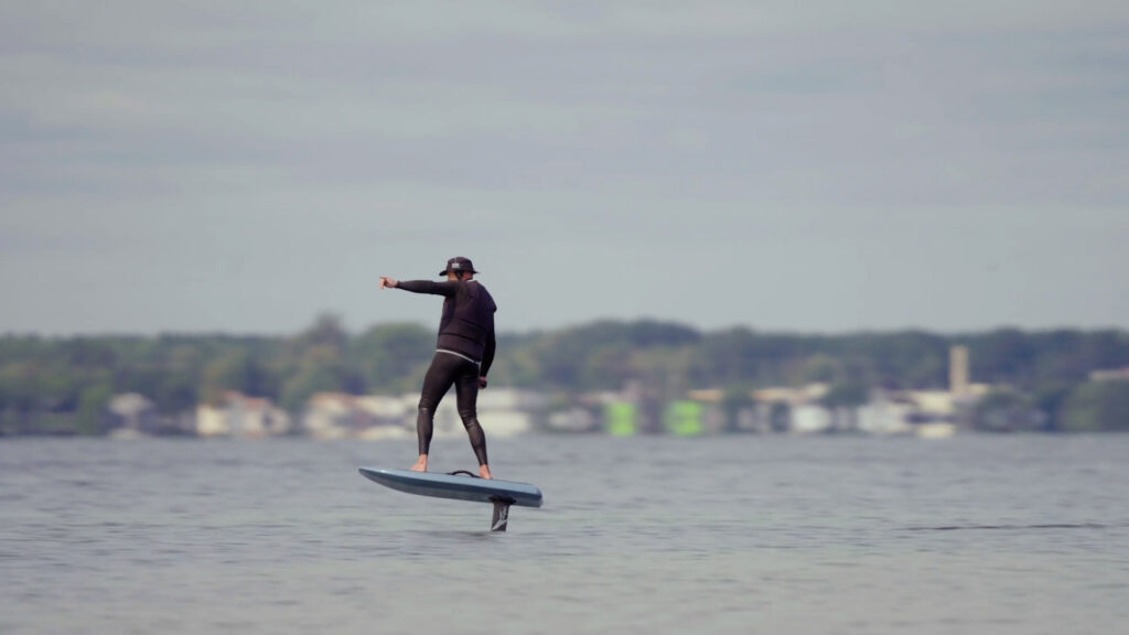 A person in a wetsuit surfing on a lake