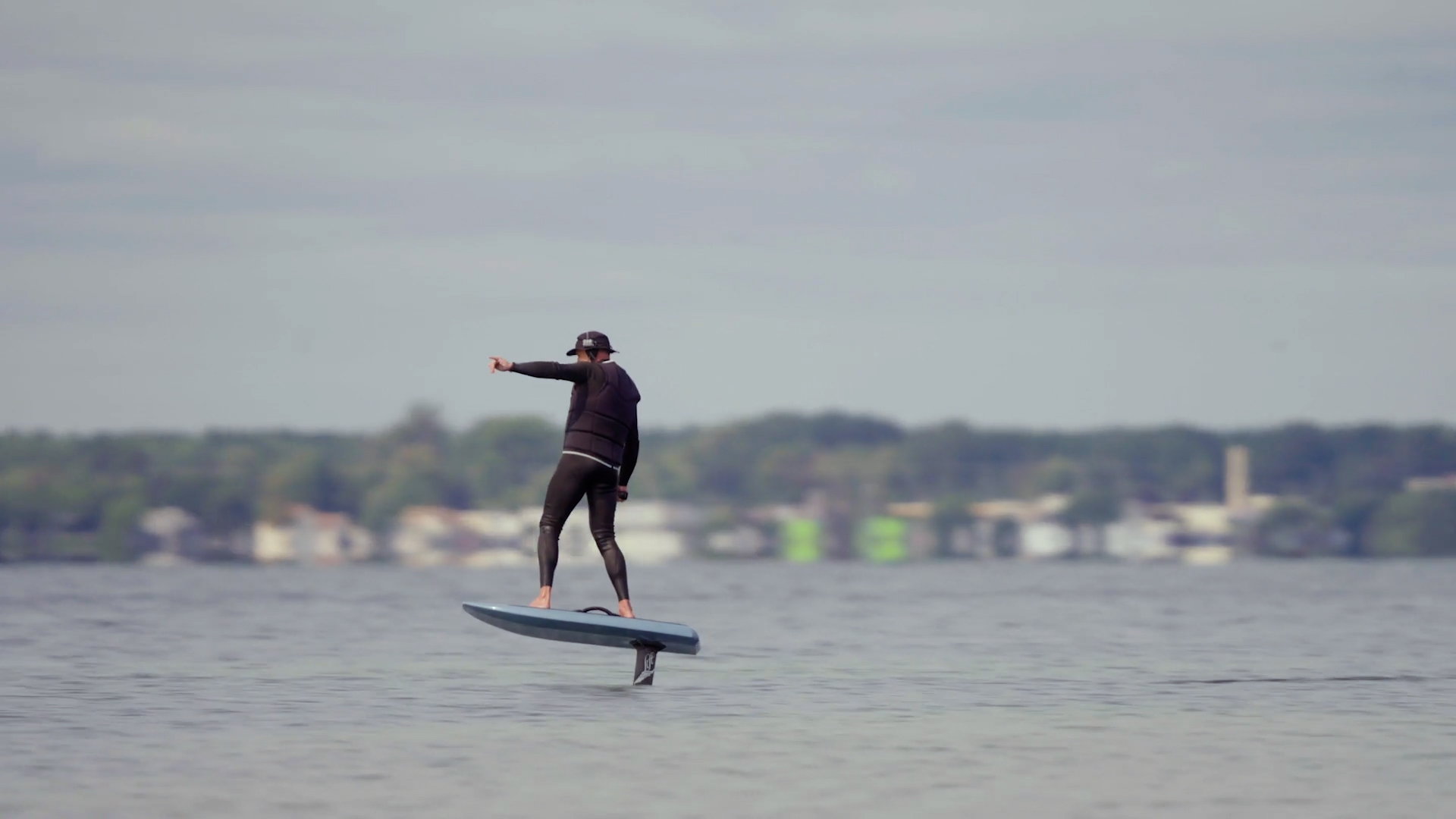 A person in a wetsuit surfing on a lake