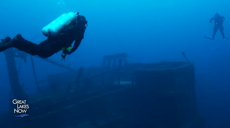 Two SCUBA divers investigate a sunken ship.