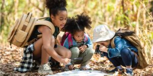 three kids looking at a map on the ground