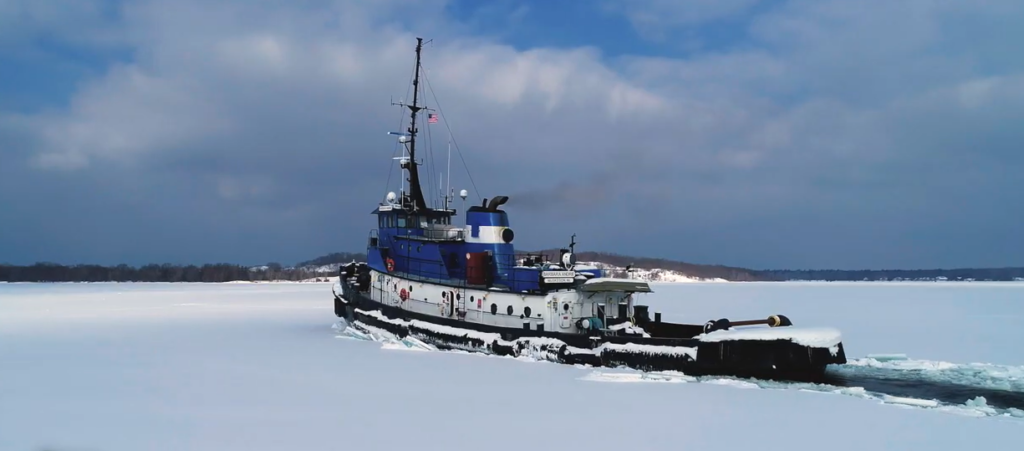 A boat navigating a lake coverd in snow and ice